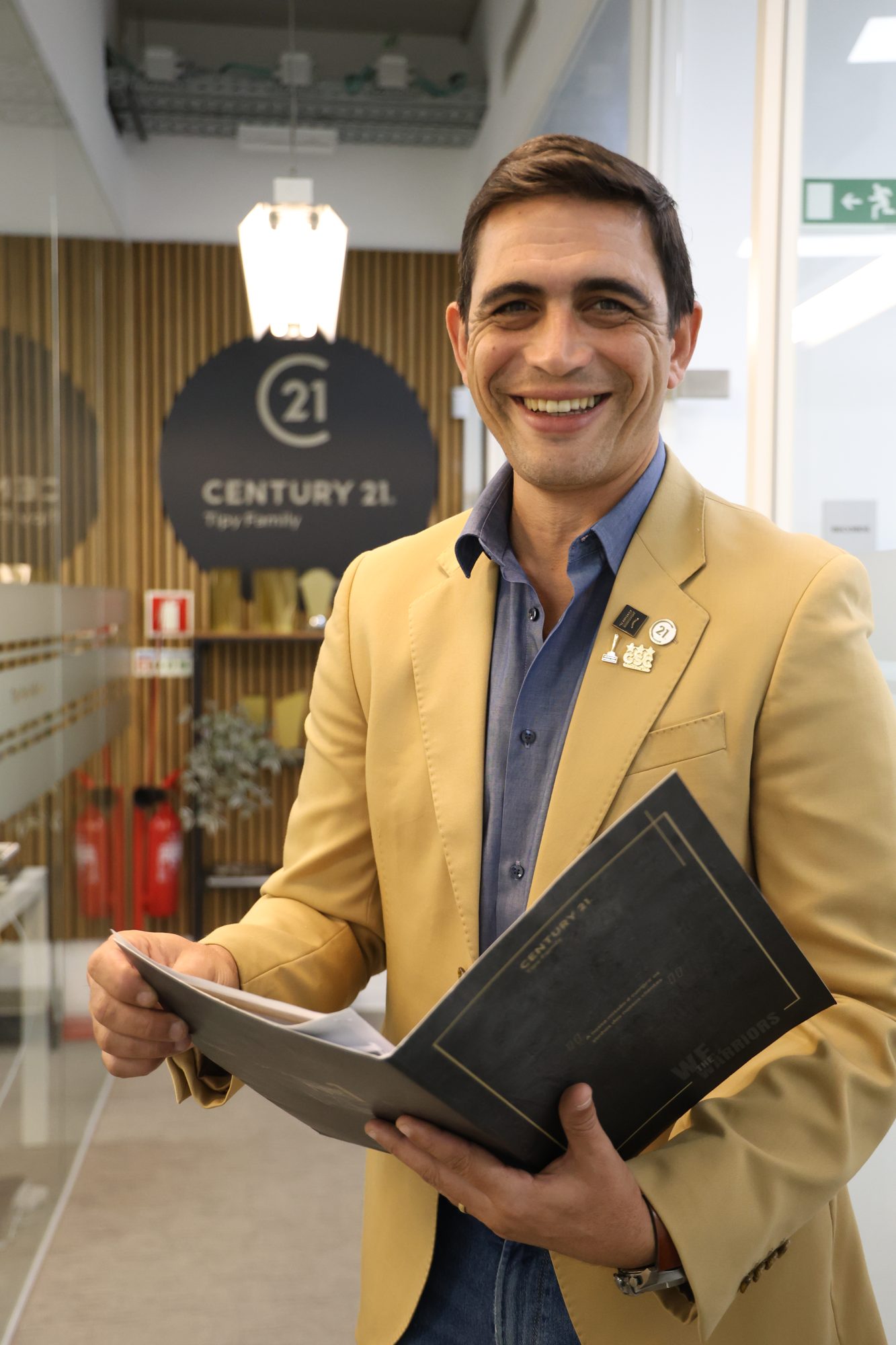 Consultor imobiliário de blazer amarelo com pasta corporativa, em escritório, fotografia de Daniel Robles