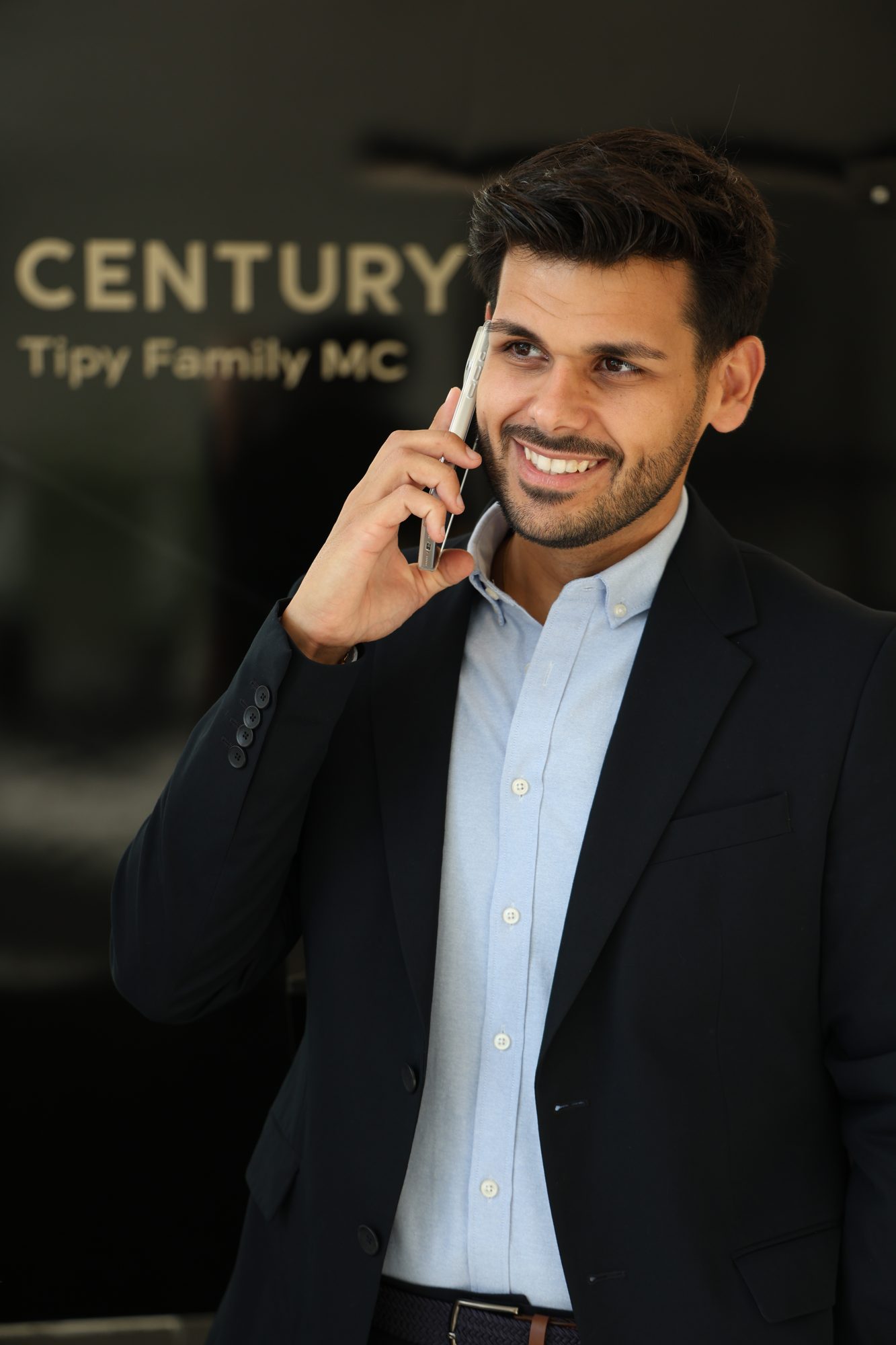 Consultor imobiliário de blazer escuro ao telefone, em escritório moderno, fotografia de Daniel Robles